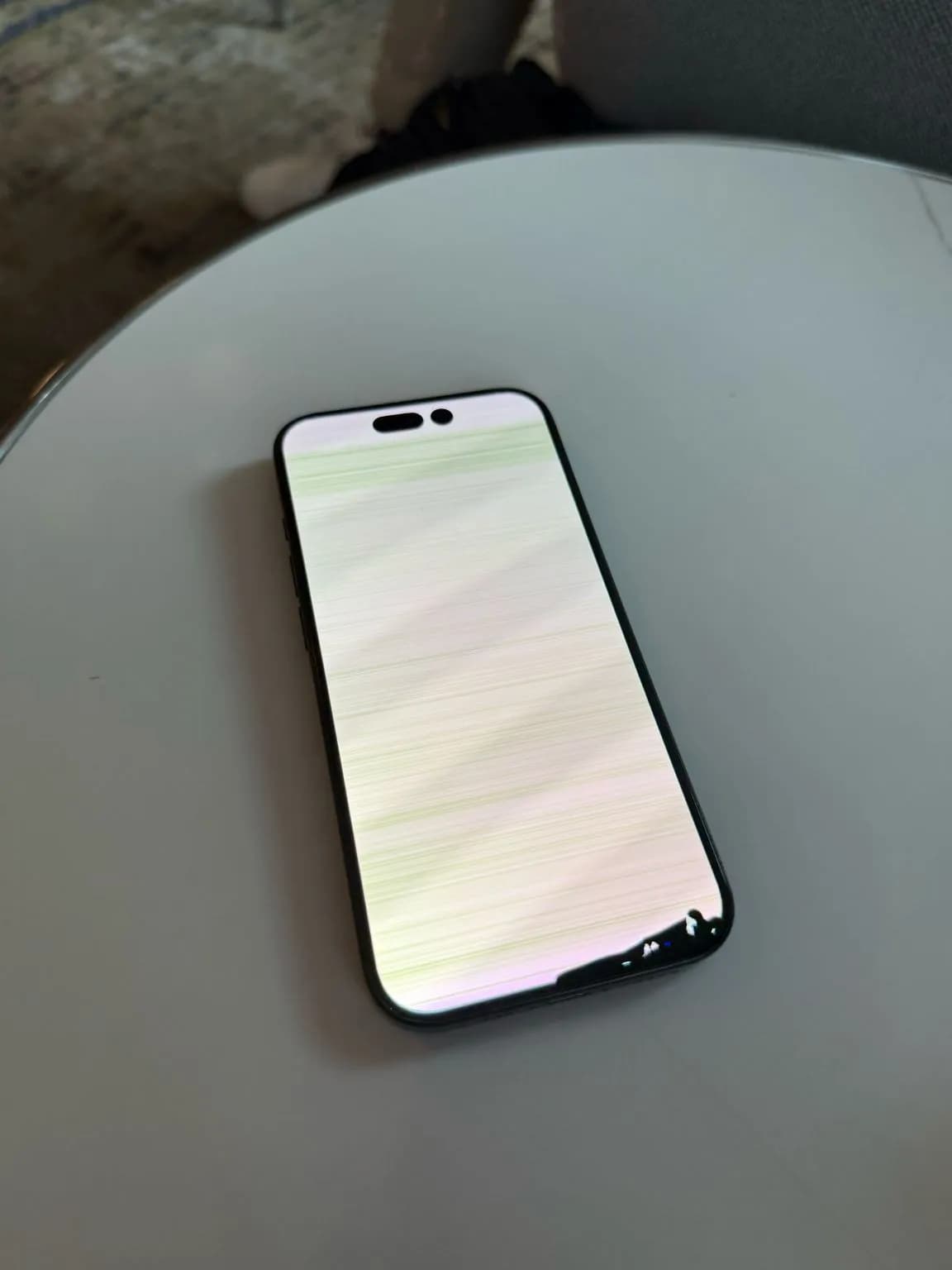 An iPhone lying face up on a round white table, screen lit.